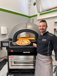 Pizzaiolo con pizza appena sfornata dal forno